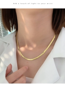Close-up of elegant gold flat herringbone snake chain choker worn on model neck