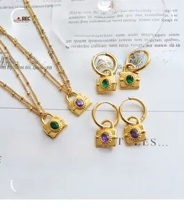 Close-up of gold chain jewelry set with emerald and purple zircon lock pendants on a book