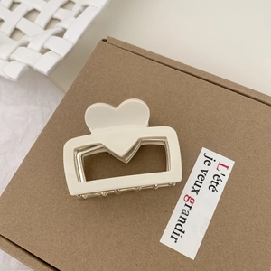 Dettaglio della molletta per capelli a cuore in acetato crema con molla dorata