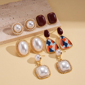 Close-up of vintage geometric earrings with faux pearls and deep red resin accents
