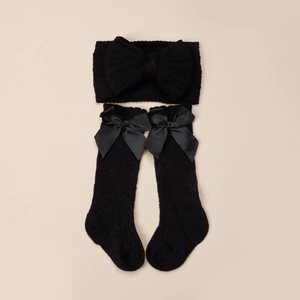 Détail d'un ensemble bébé avec bandeau à nœud noir et chaussettes longues en tricot noir