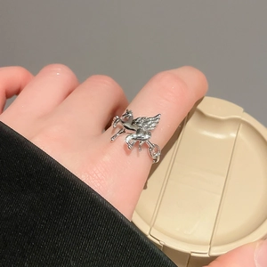 Macro detail of a silver winged Pegasus open ring worn on finger showing fine craftsmanship