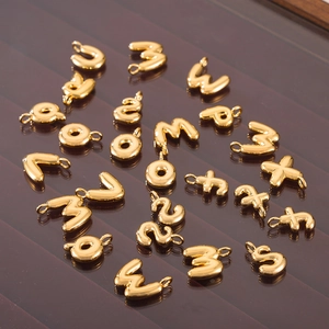 Golden 3D puffy balloon style alphabet and number pendants on a dark wood surface