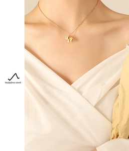 Detailed view of a gold elephant pendant necklace worn by a model in soft lighting
