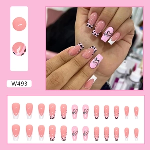 Faux ongles ballerine roses avec motifs de cœurs noirs et imprimés de lait