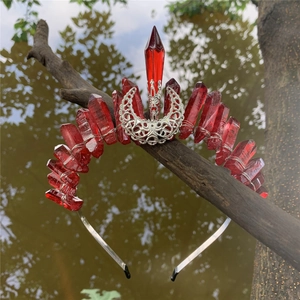 Detailed shot of red raw crystal crown with silver crescent moon moon on a branch