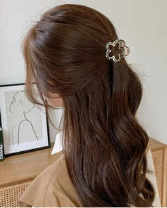 Close-up of a green flower hair claw clip with gold edges on a model's hair