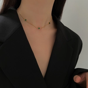 Close-up of elegant 18K gold plated necklace with three square green zircon pendants