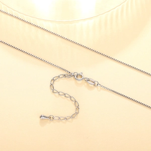 Detail of silver box chain necklace featuring a spring clasp and teardrop pendant