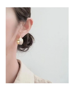 Close-up of elegant 18K gold plated earrings with white enamel finish on a model