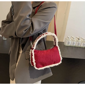 Detail of burgundy faux suede shoulder bag with plush white faux shearling trim accents