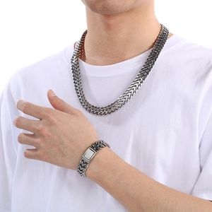 Detailed view of silver stainless steel woven chain necklace and bracelet set on a model