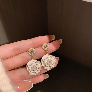 Makroaufnahme von Kamelienohrringen mit weißen Blüten, Perlen und glitzernden Kristallen