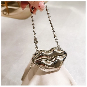 Detail of silver metallic lip-shaped mini bag with chain strap and flower accents