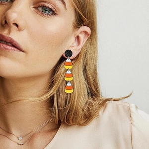 Close-up of a model wearing candy corn dangle earrings for Halloween theme