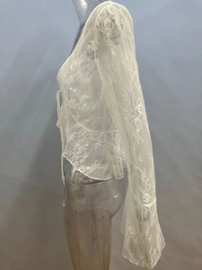 Dettaglio cardigan bianco in pizzo a maniche lunghe con rete floreale e volant sui polsi