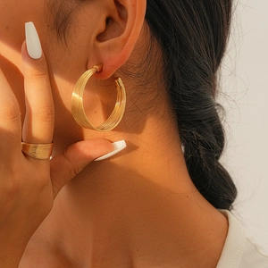 Nahaufnahme eleganter goldener mehrlagiger Creolen und passendem Ring am Model