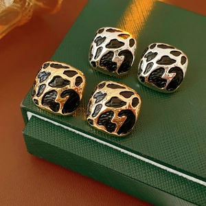 Détails de boucles d'oreilles carrées léopard dorées et argentées sur écrin bijoux