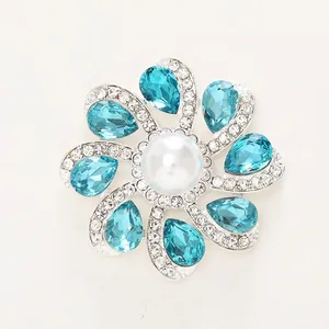 Elegant flower brooch with blue crystals and a central white pearl for jewelry decor