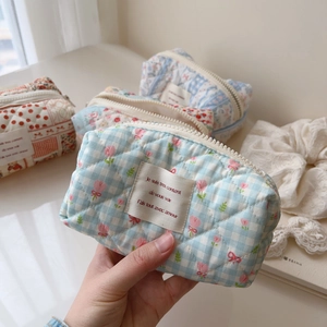 Detailed close-up of a quilted cotton floral makeup bag with a zipper and fabric label