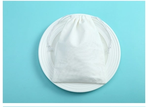 Close-up of white cotton drawstring pouch for jewelry storage on a blue background