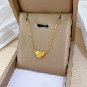 Macro detail of a 3D gold heart pendant on a delicate snake chain inside a jewelry box