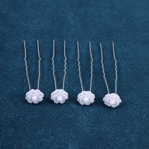 Detailed view of four white floral resin hair pins with wavy metal U-shaped grips