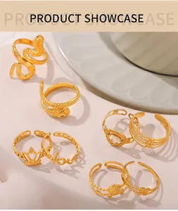 Detail view of gold snake, crown, and love letter rings set on a marble surface