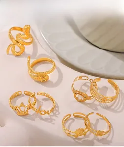 Detail view of gold snake, crown, and love letter rings set on a marble surface