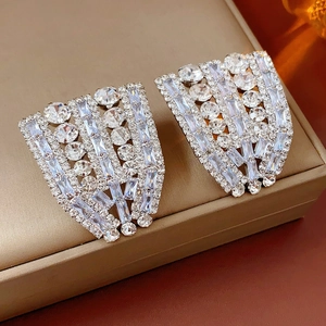 Détail de grandes boucles d'oreilles argentées en éventail avec incrustation de zircon