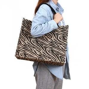 Zebra print jute tote bag with black shoulder straps shown on a model against white background