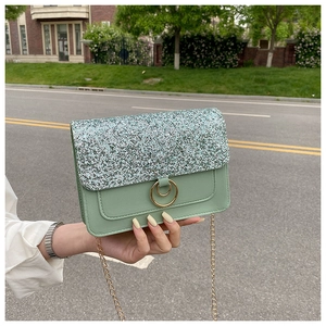 Close-up of a green sequin flap bag with gold chain strap and ring buckle details