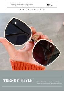 Close-up of oversized square sunglasses featuring thin gold metal frames and dark lenses