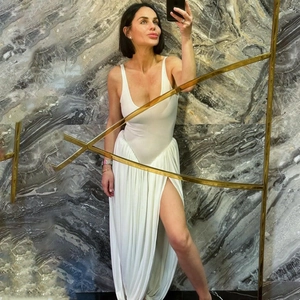 Mirror selfie showing the side slit detail of a sexy white backless back long dress