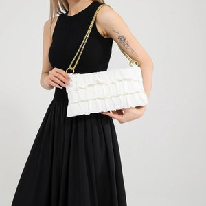 Minimalist white pleated shoulder bag with gold chain strap shown on a model