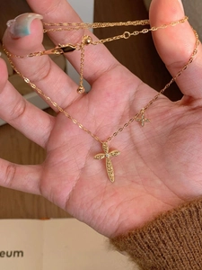 Macro shot of 24K gold plated cross pendant necklace with clover detail and micro-pave stones