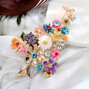 Macro detail of Christmas tree brooch featuring colorful rhinestones and gold enamel