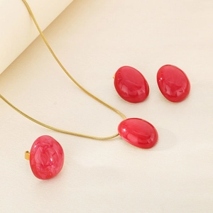 Detailed set of deep red enamel jewelry with gold snake chain and marble texture ring