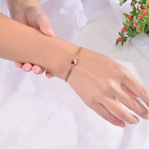 Bracciale a proiezione in oro rosa per donna indossato al polso su uno sfondo di tessuto bianco