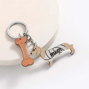 Detail van teckel sleutelhanger met mom-print en bot bedeltje op witte houder