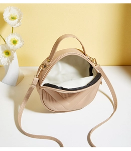 Top view of beige round crossbody bag with V-shaped quilted embroidery and open interior