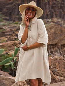 Detail of loose beige linen shirt dress with polo collar and buttons in resort setting