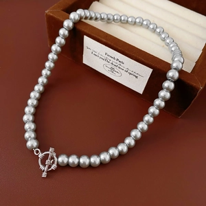 Detail of silver gray pearl necklace featuring a metallic OT toggle clasp closure