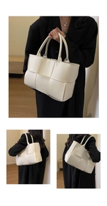 Detailed close-up showing the wide leather woven texture and dual handles of the white tote