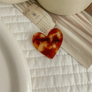 Detail of heart-shaped acetate hair clip with tortoise shell pattern and handmade text