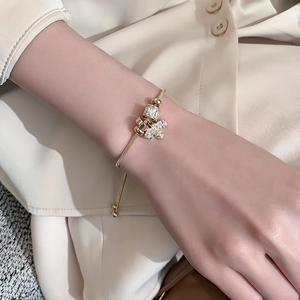 Goldenes Schlangenarmband mit Zirkonia-Perlen und Bienen-Anhänger an einem Handgelenk
