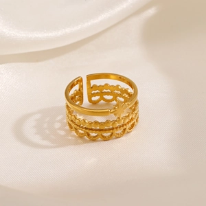 Three-layer gold stainless steel ring with star accent and wavy patterns on silk cloth