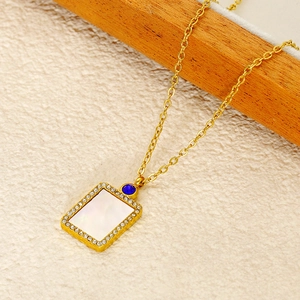 Detailed macro of gold shell pendant necklace with zircon halo and blue gemstone accent