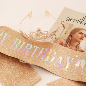 Close-up of golden glitter sash with HAPPY BIRTHDAY text and rhinestone tiara set