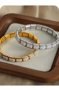 Dettaglio di bracciali charm italiani in oro e argento con pavé di strass luccicanti